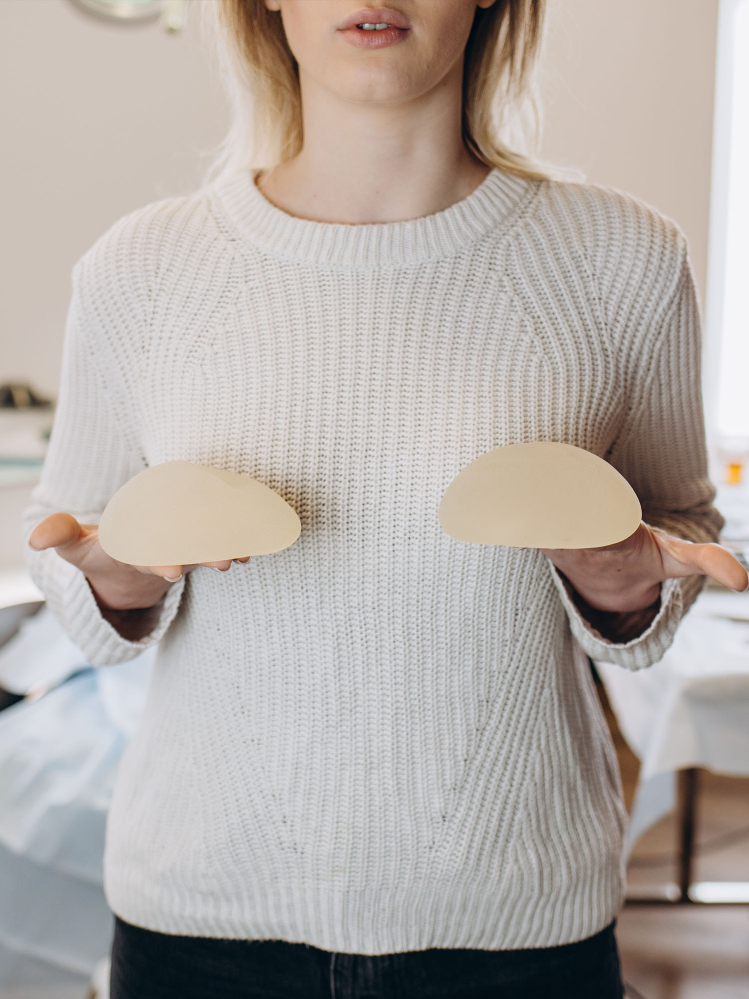 A woman holding pads for a breast augmentation.